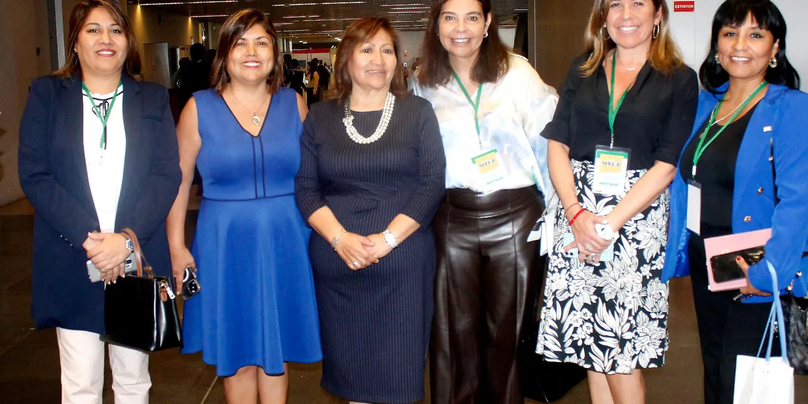 Seis empresarias posan con sus acreditaciones en un pasillo del evento de la Semana de la MYPE