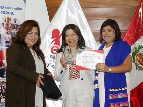 Tres mujeres posan con un trofeo de cristal y un certificado a nombre de Luz Caballero Morales