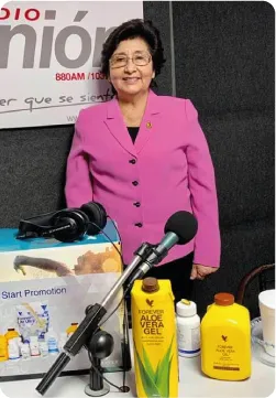 Retrato de Fanny Huapaya de Alaña en un estudio de radio junto a productos de aloe vera