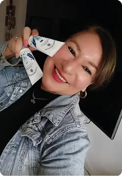 Retrato de Lucy Tuesta sosteniendo productos de cuidado de la piel
