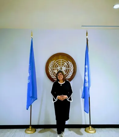 Integrante de la red en la sede de las Naciones Unidas, entre dos banderas de la ONU.