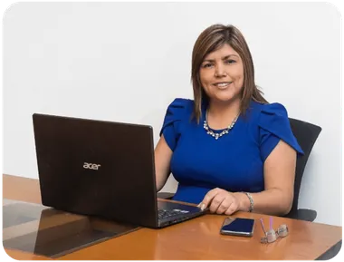 Mujer sonriente sentada ante una laptop en su escritorio.