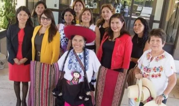 Grupo de empresarias peruanas posando frente a un edificio, con una mujer en traje típico al centro